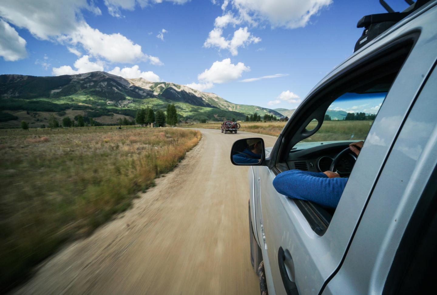 View out the side of a car driving down a dirt road
