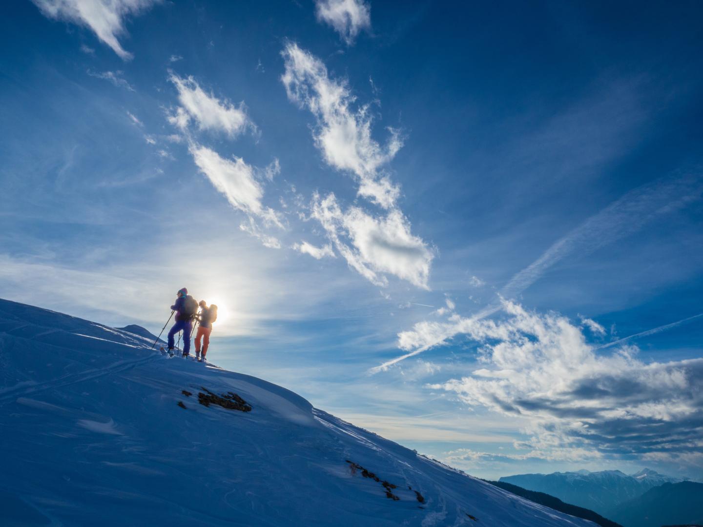 Two people ski touring on top of a mountain