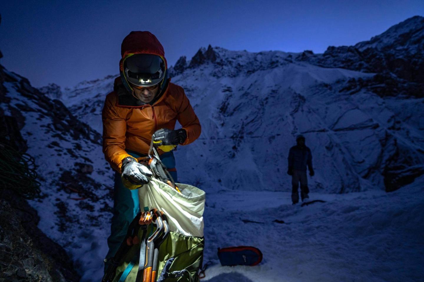 A climber in a mountain range at night