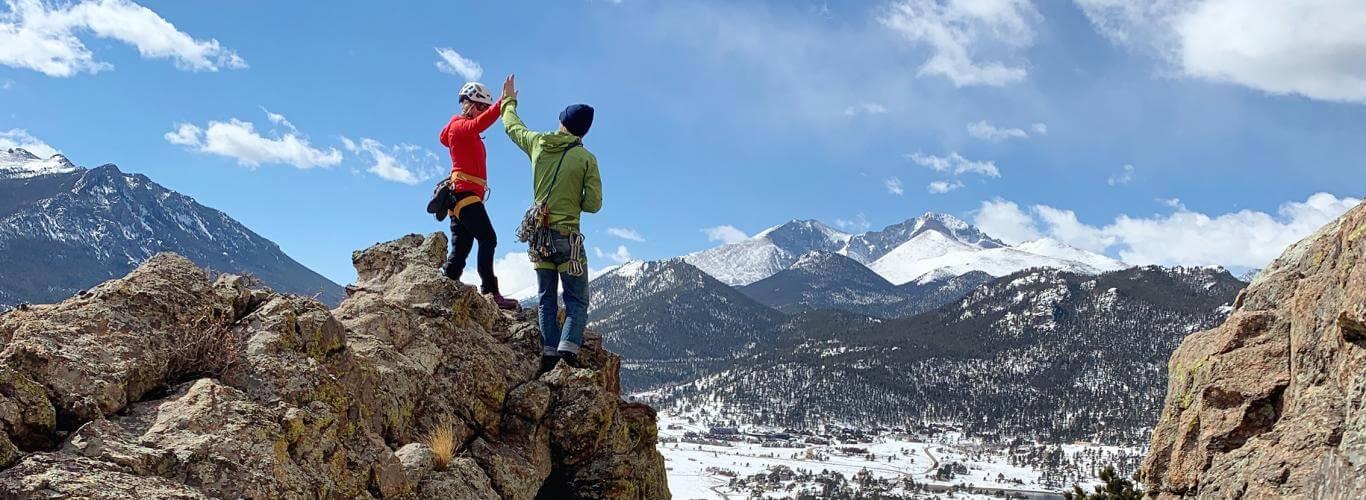 Two climbers high fiving on top of a mountain
