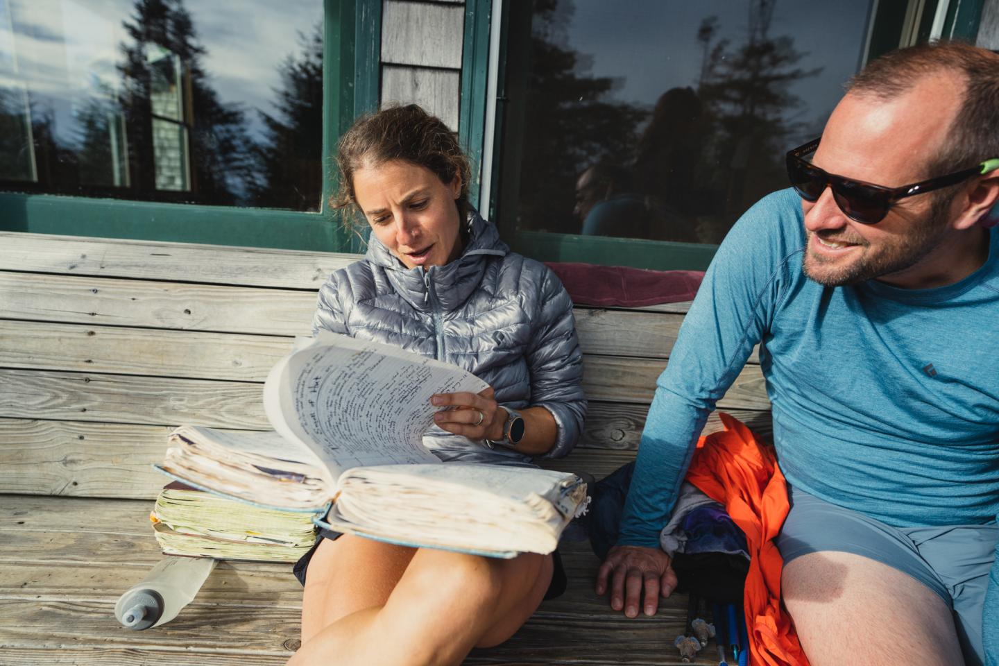 Trail runner flipping through a big guest book at a backcountry hut