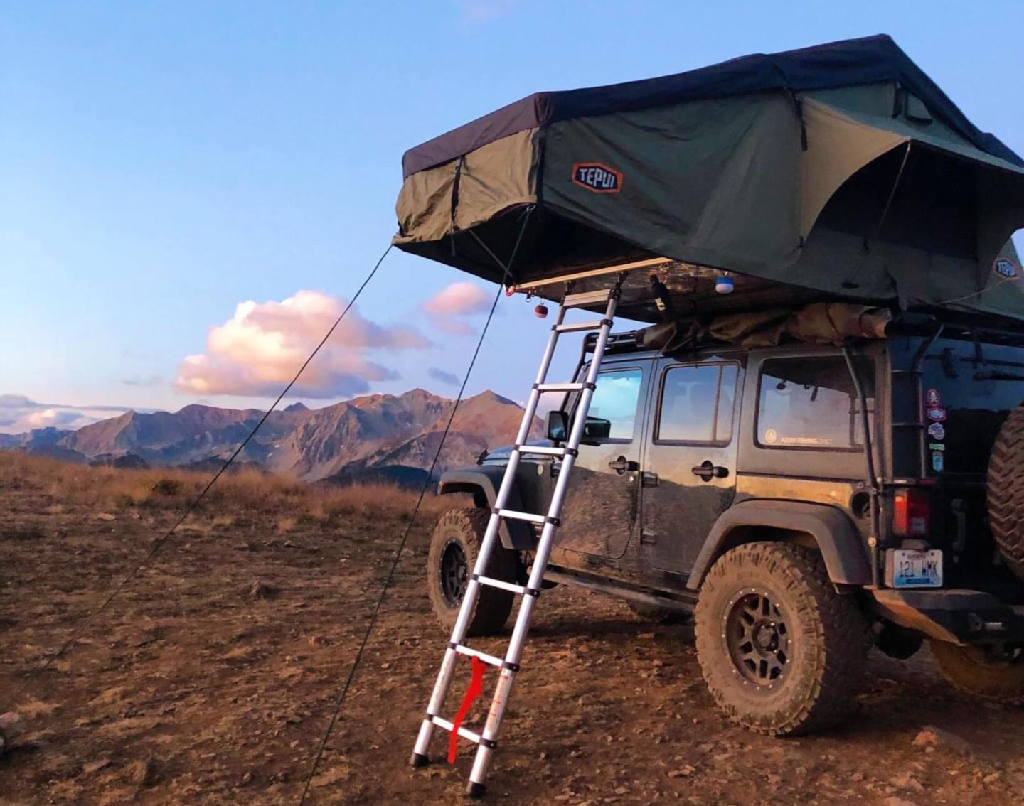 A Jeep with a rooftop tent overlooking the mountains