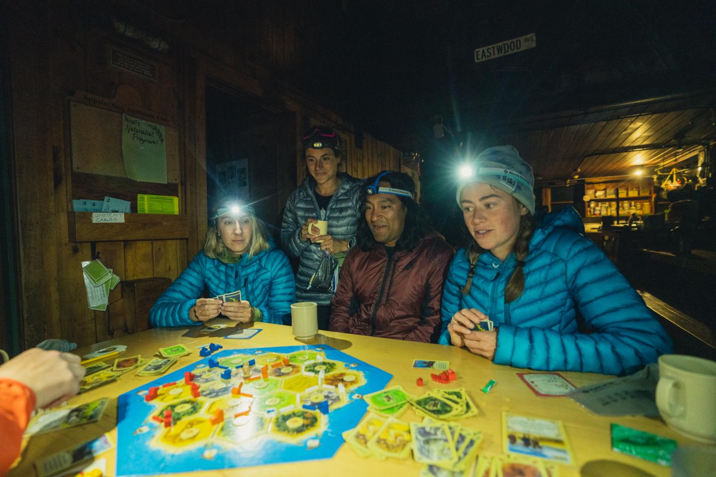 Group playing Catan with headlamps in a backcountry hut
