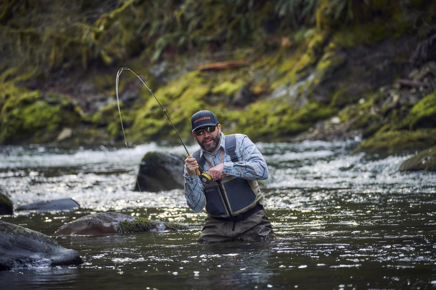 fly fisherman in the water catching a fish