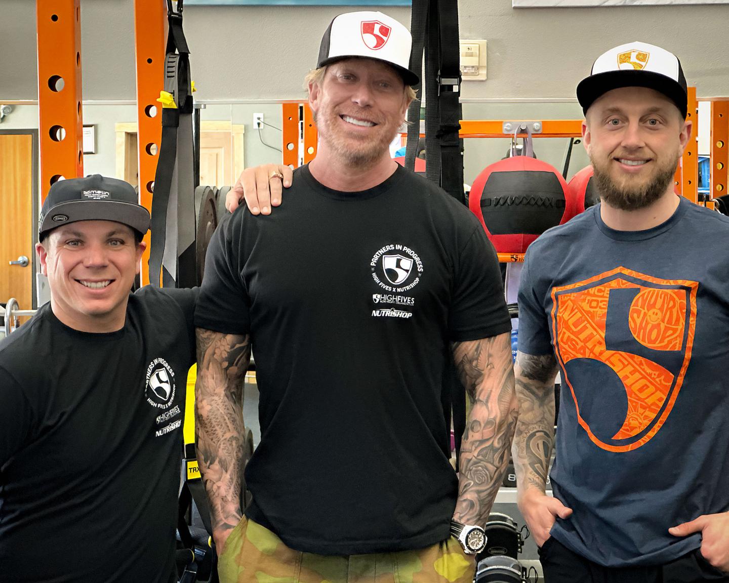 Three people in a gym smiling