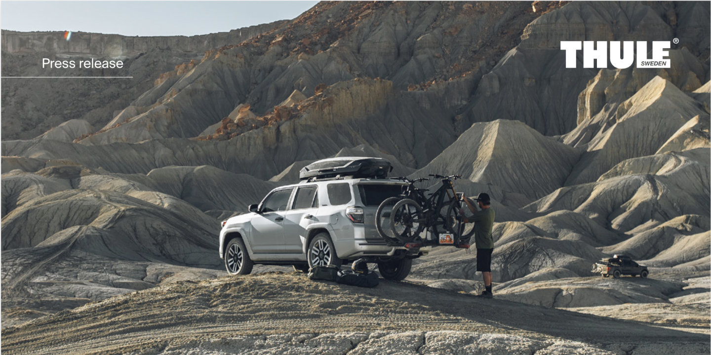 SUV with a bike rack in a rocky landscape, person standing beside it.