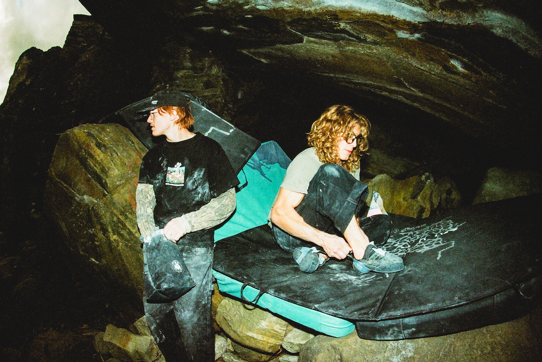 Two people resting on climbing pads inside a cave.