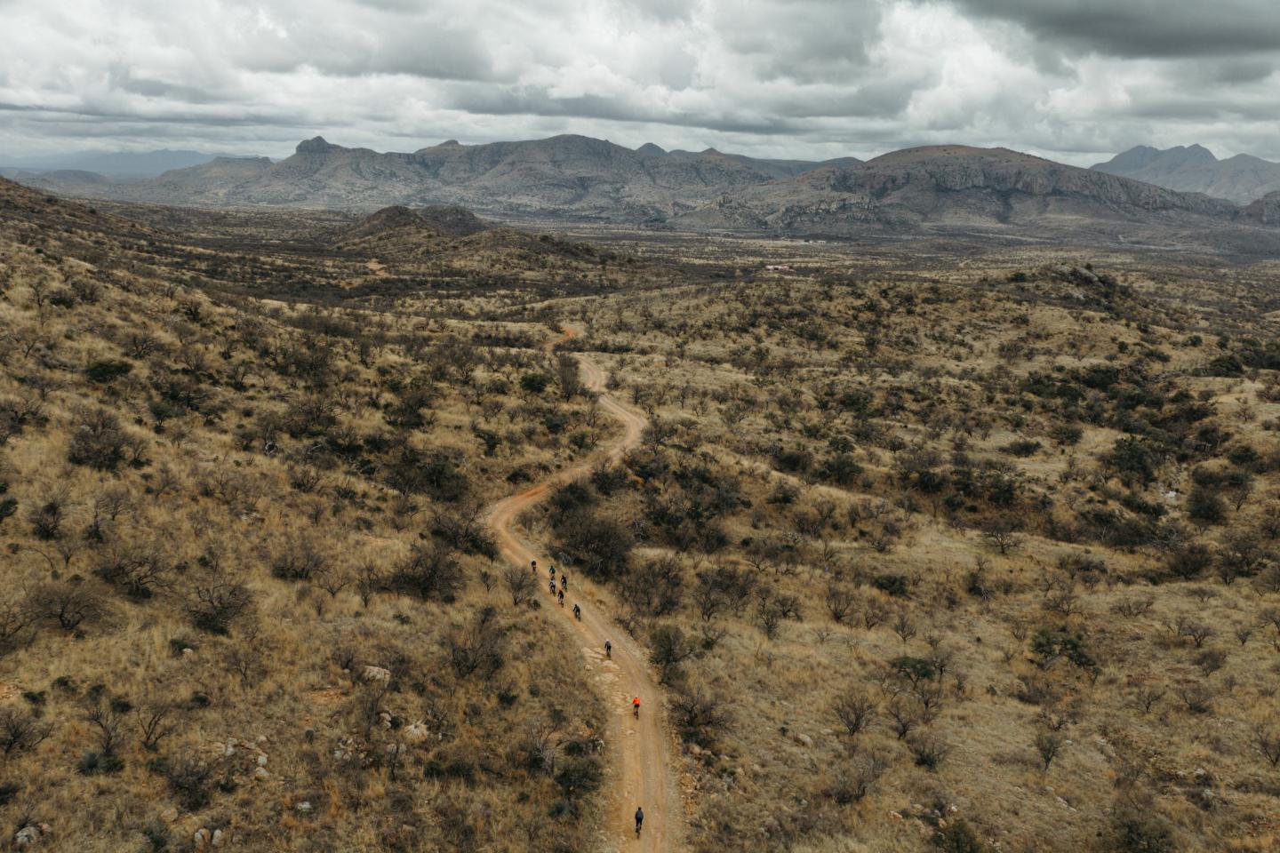 Aerial view of a dry, mountainous landscape with a winding dirt path.