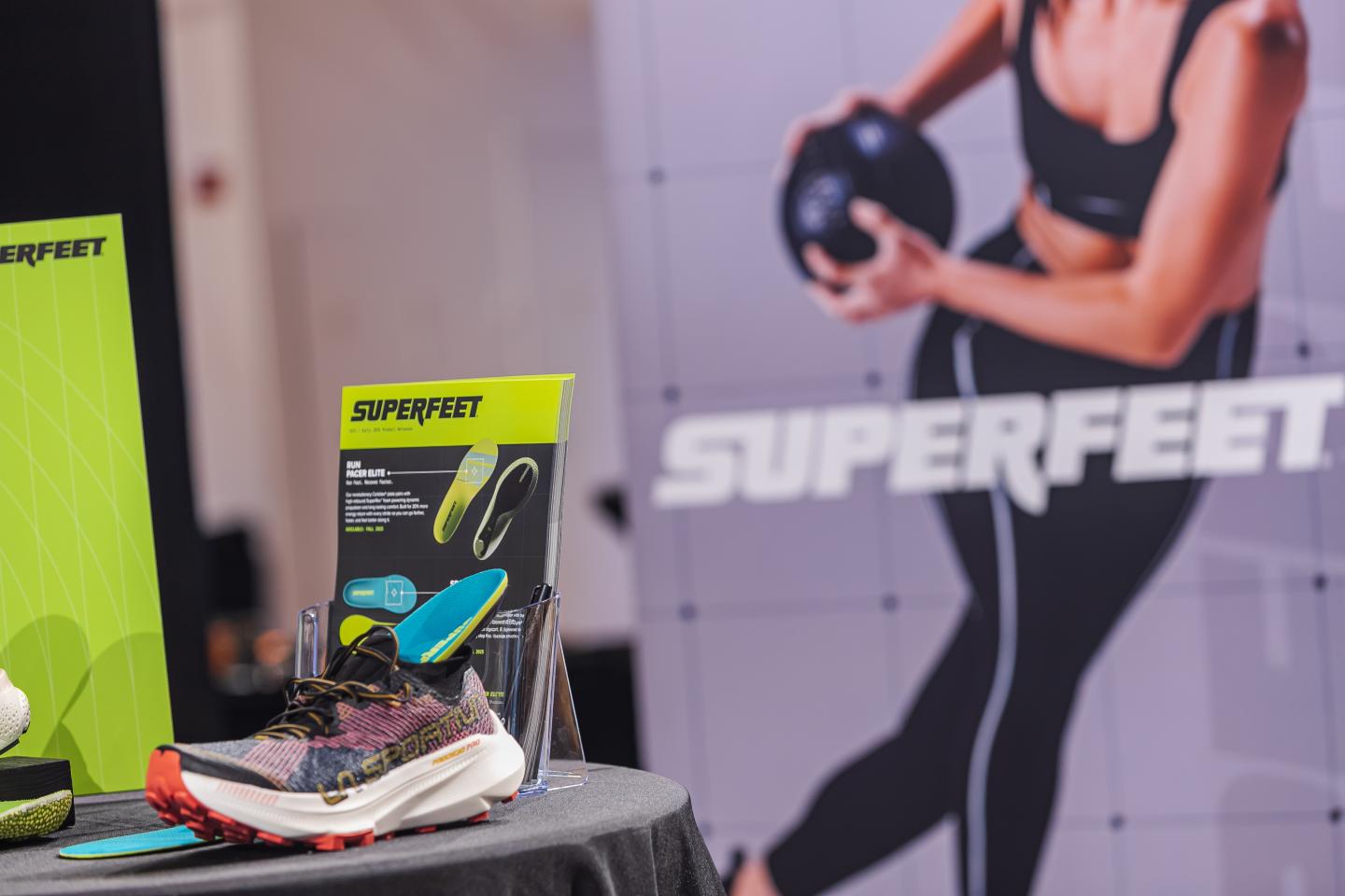 A display of Superfeet insoles and a woman exercising in the background.