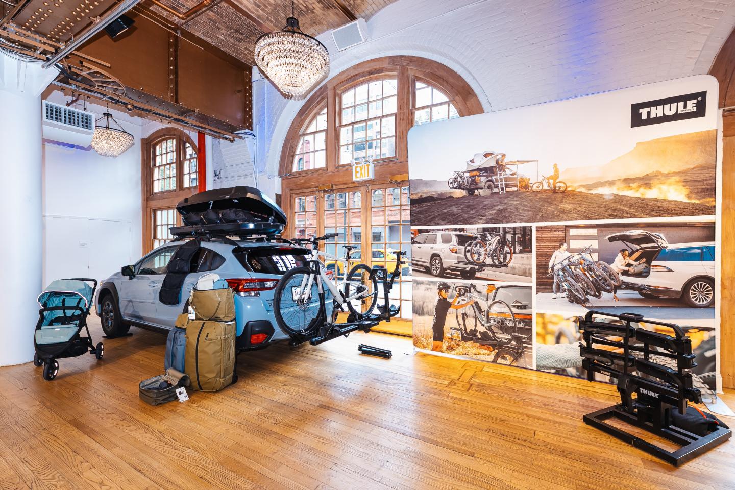 Car with bike racks and travel gear on display indoors.
