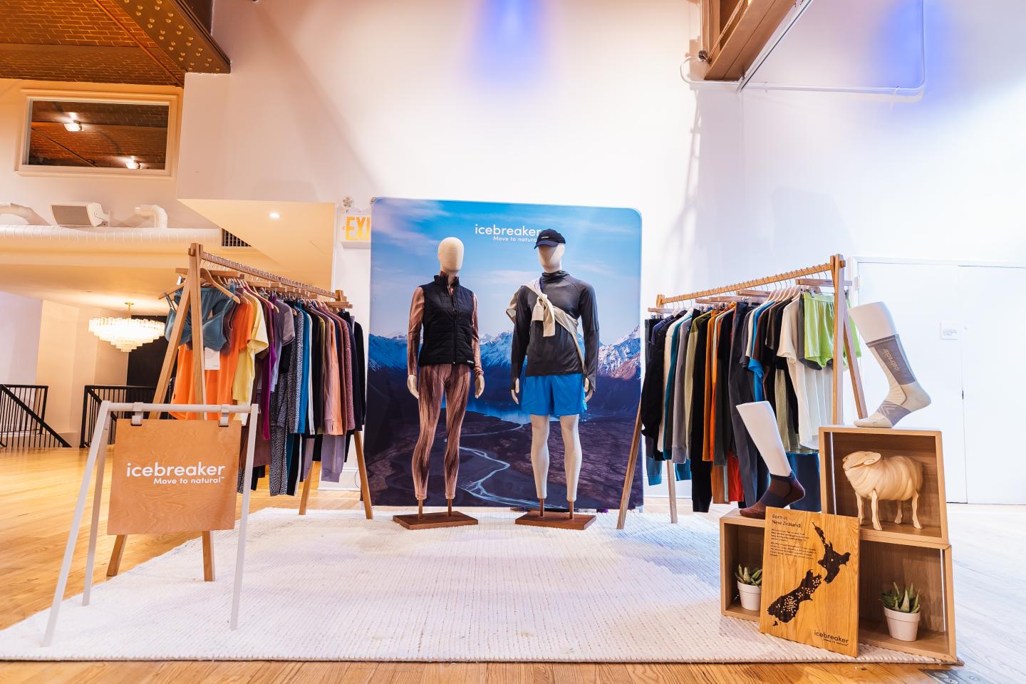 Clothing display with two mannequins and racks, in a bright exhibition space.
