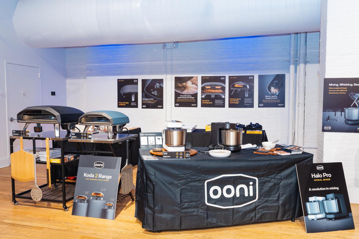 Exhibit booth with pizza ovens and cookware displayed.