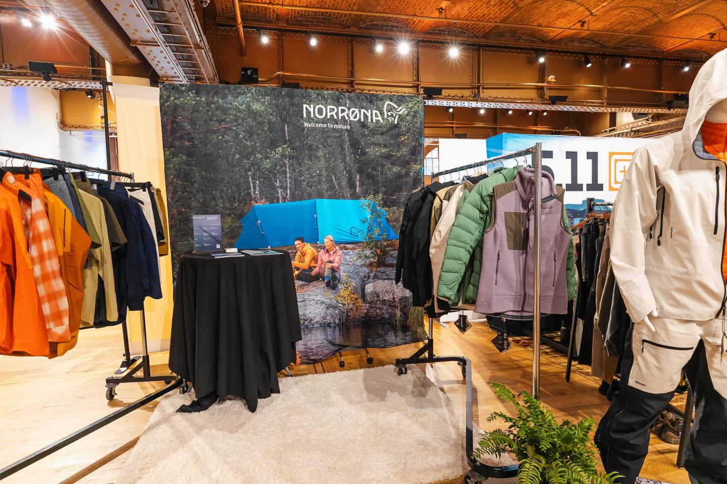 Clothing display in a rustic wooden room with jackets and coats on racks.
