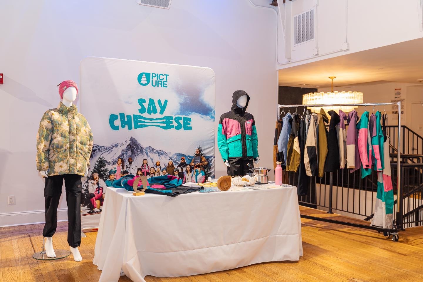 Mannequins in winter wear, clothes rack, and table with accessories in a showroom.