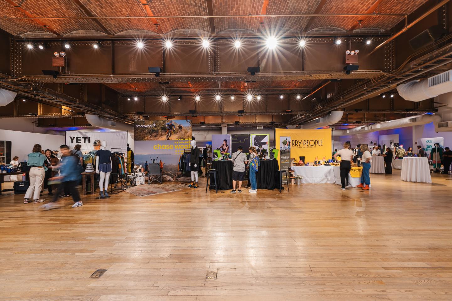 Spacious event hall with people mingling near booths.