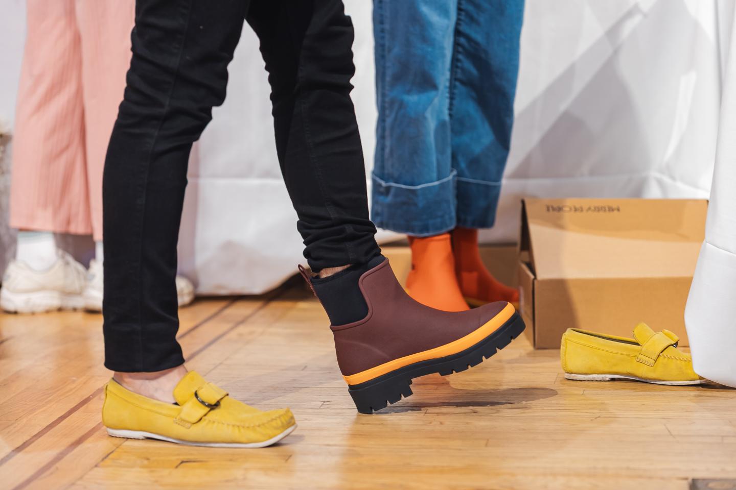 Colorful shoes on feet, including yellow loafers and brown boots with orange accents.
