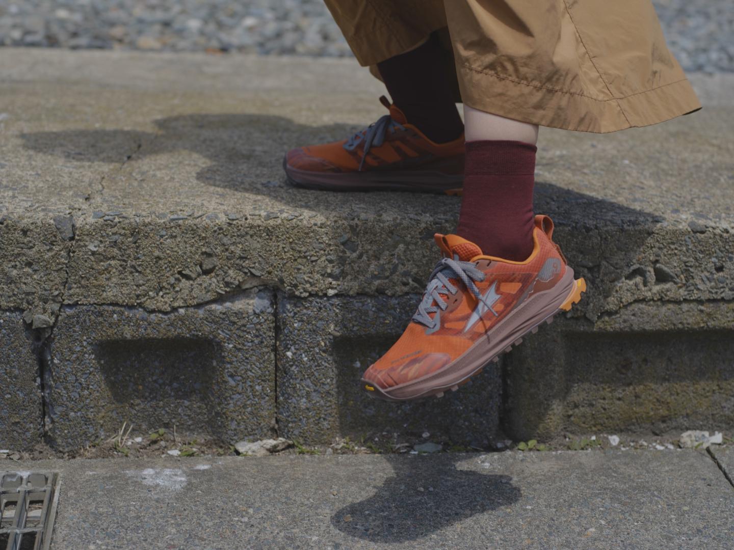Stepping down in orange sneakers and brown pants.