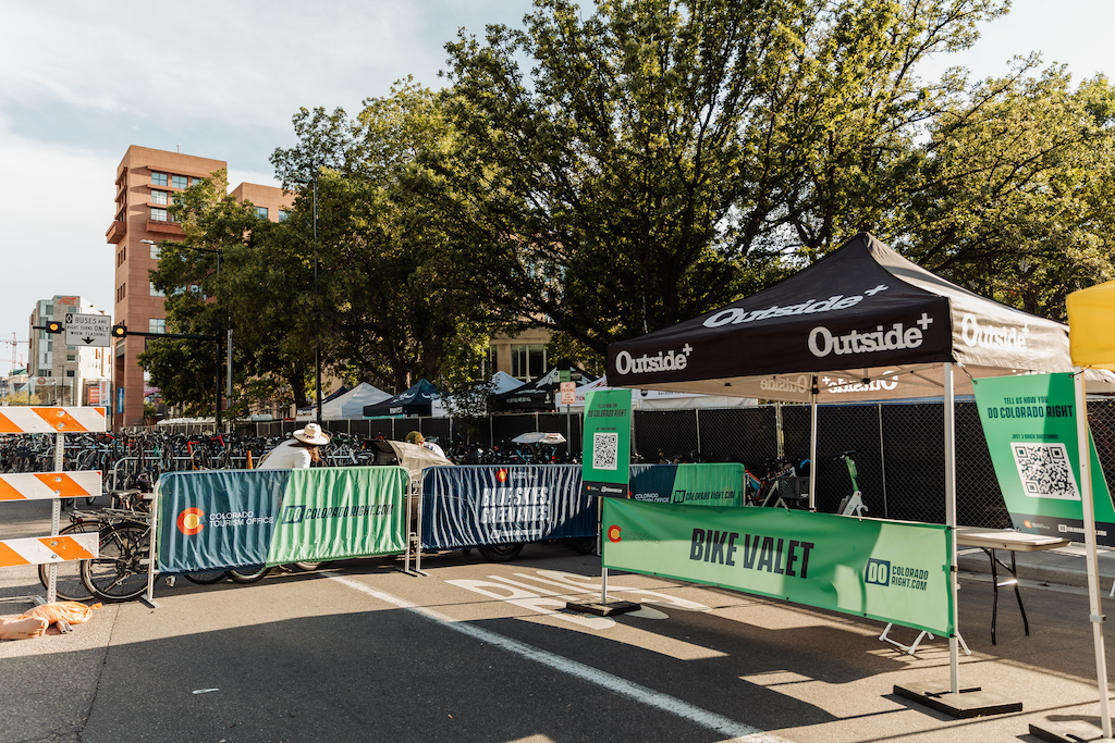 Street setup with tents, green barriers, and trees under a blue sky.