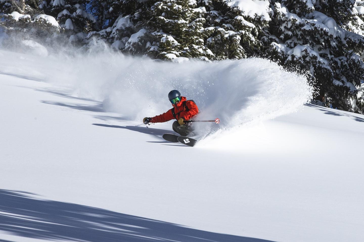 Skier wearing the BD Recon Kit, taking a deep powder turn on BD Helio Carbon skis