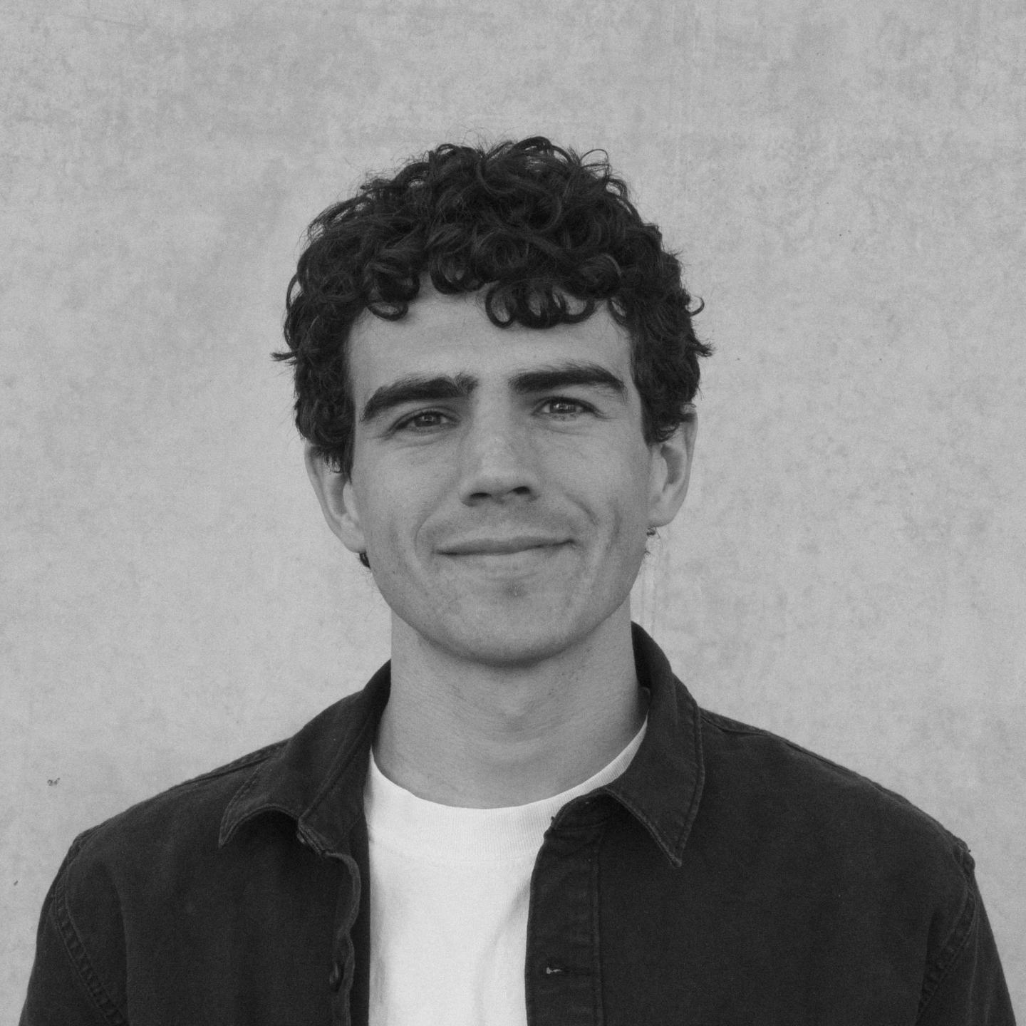 Curly-haired person smiling in black and white photograph.