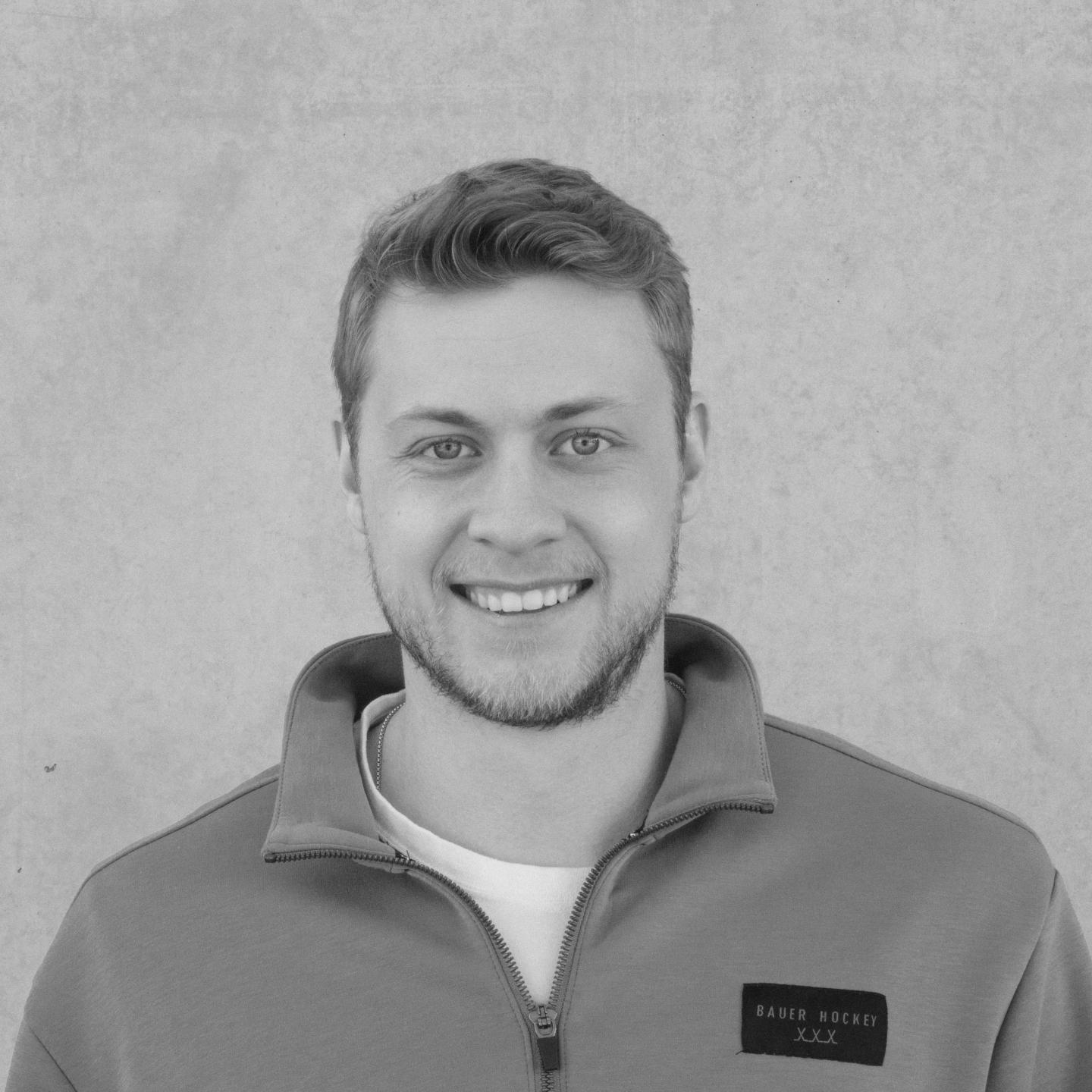 Smiling man in a casual jacket, gray background.