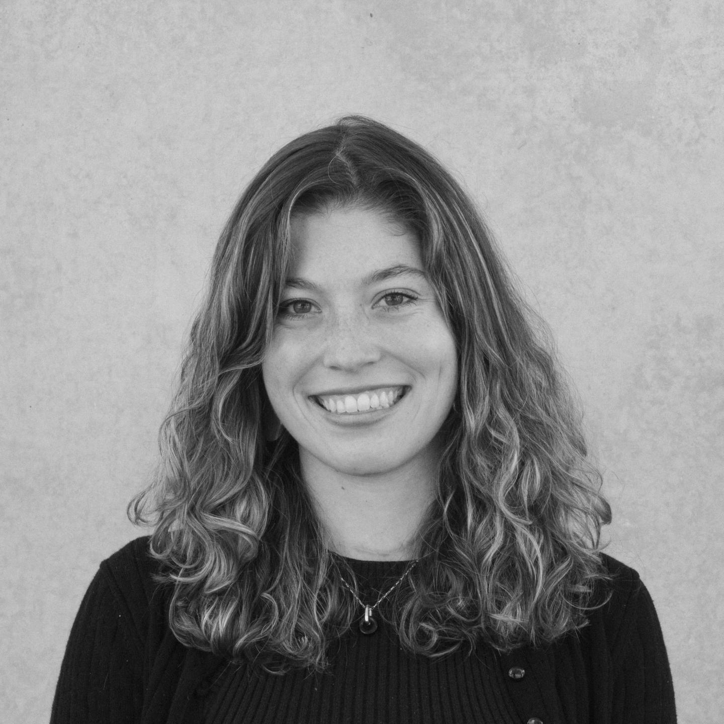 Smiling woman with curly hair in a black and white photo.