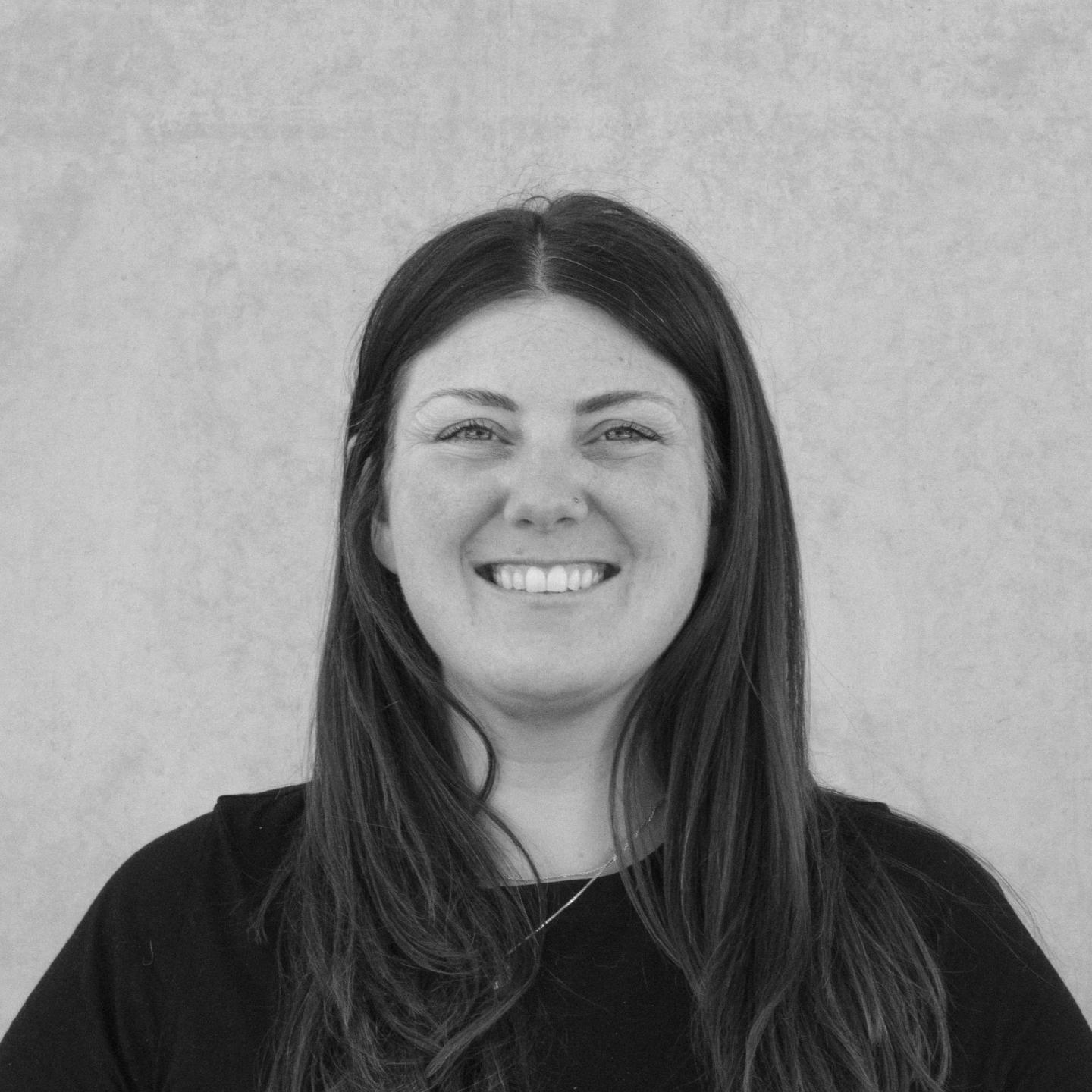 Smiling person in a black shirt, against a light gray background.