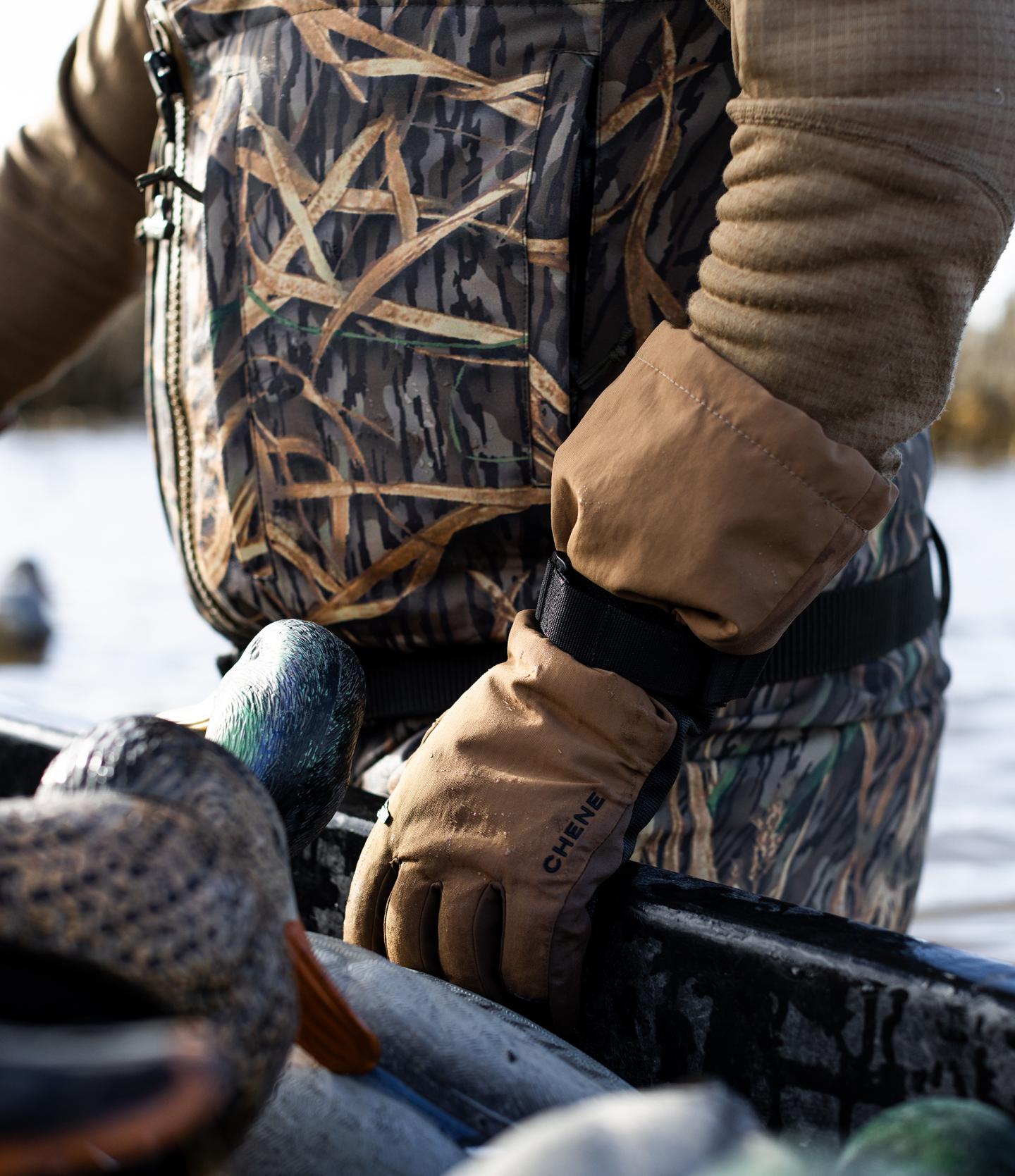 Camouflaged person holding decoy ducks in a boat on the water.