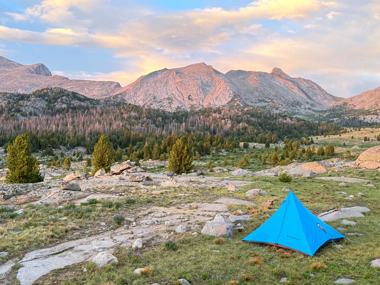 Blue Black Diamond tent in mountainous landscape with sunset sky.