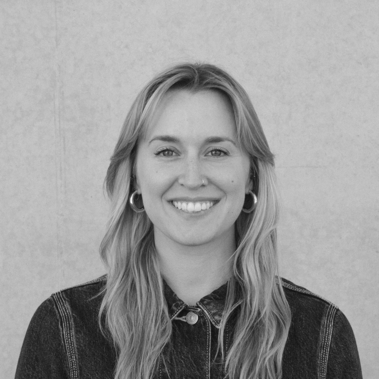 Smiling person in a denim shirt, black-and-white portrait.