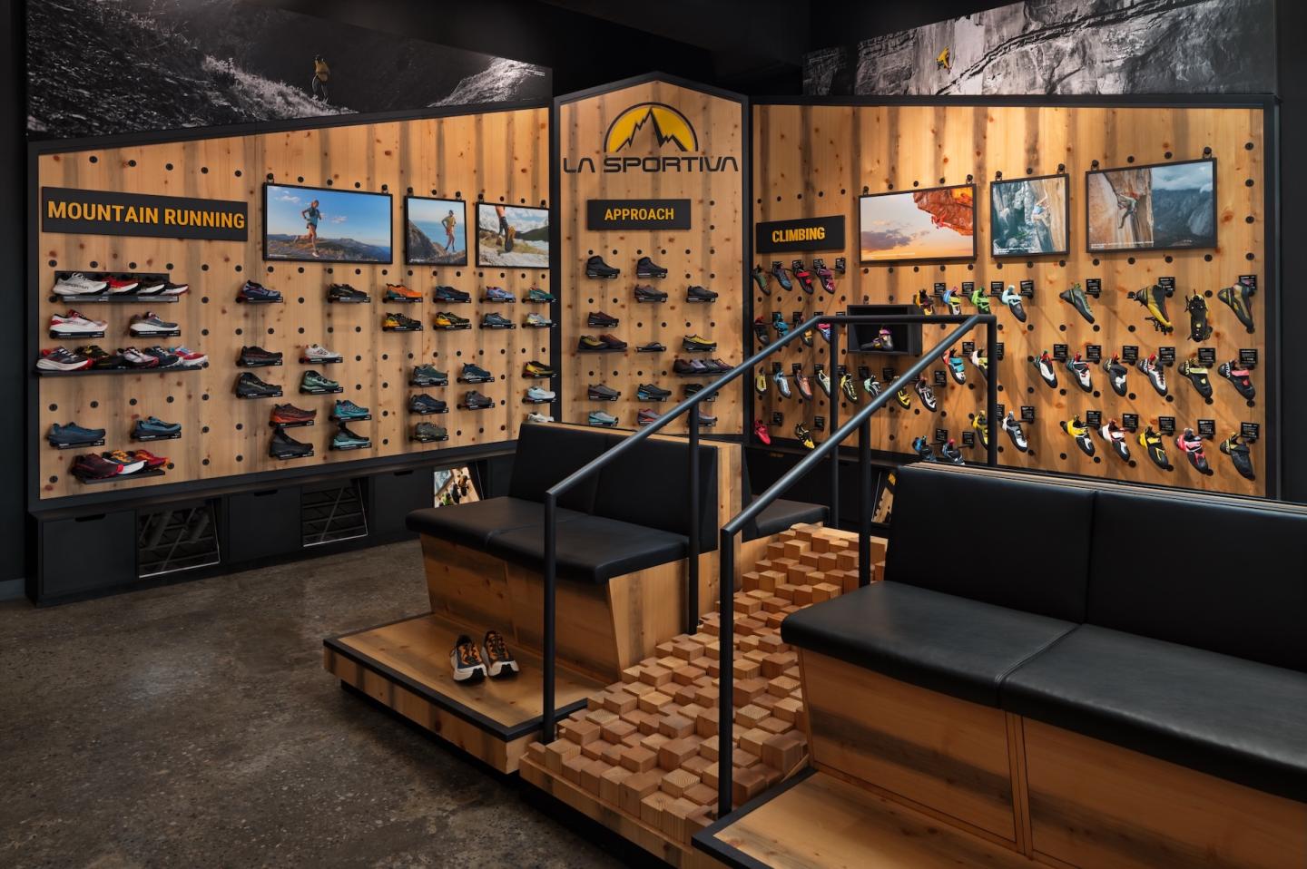 Shoe store display with black couches and wooden shelves showcasing various footwear.