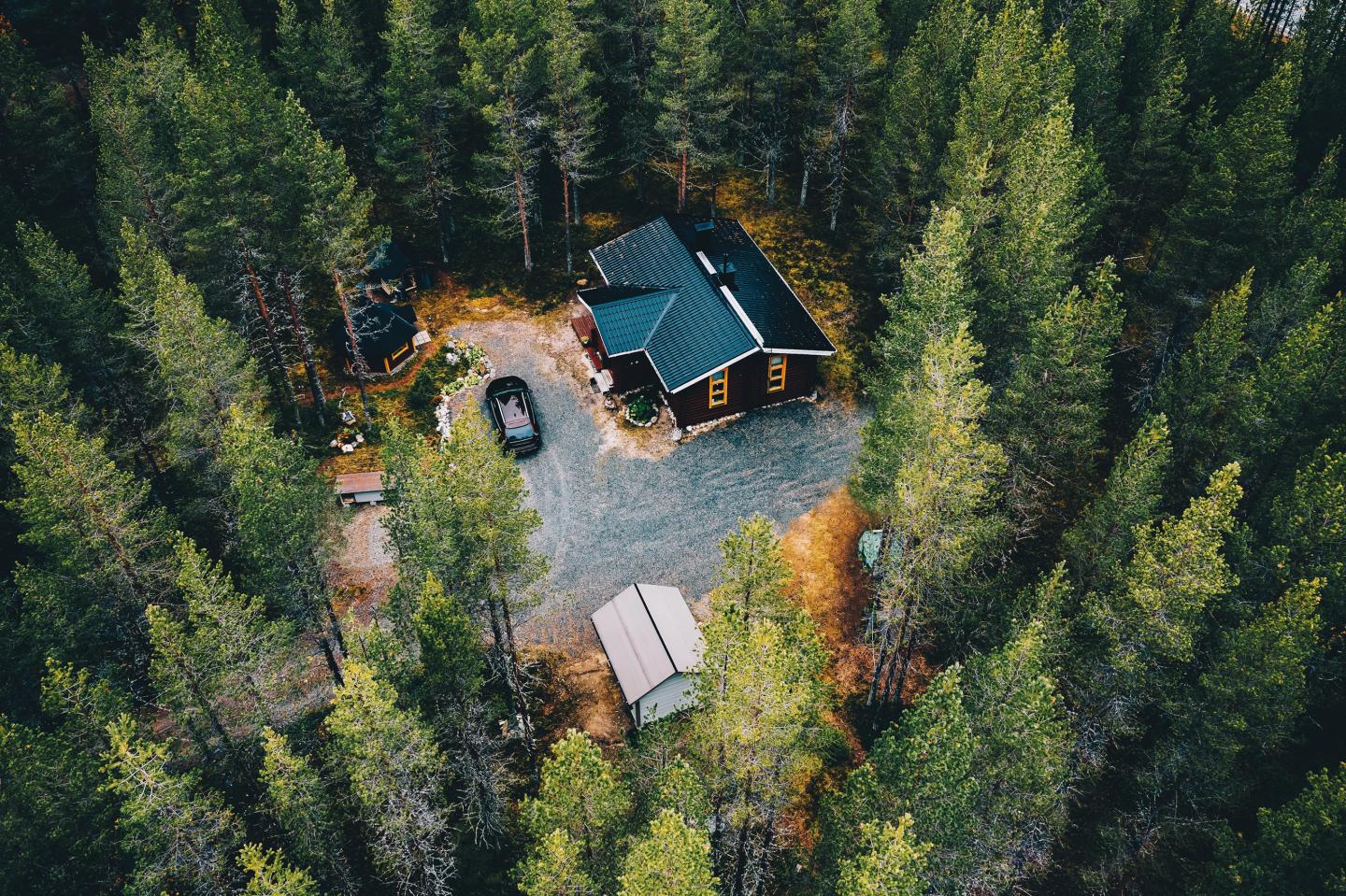 Aerial view of a cabin surrounded by dense evergreen forest.